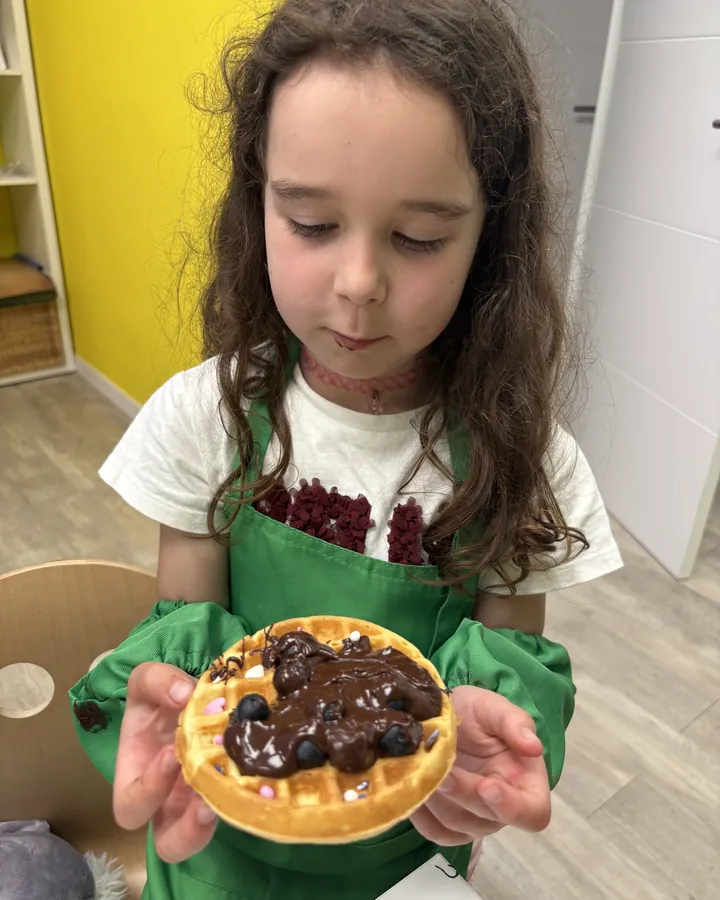 Niña con un gofre de chocolate en el taller de gofres