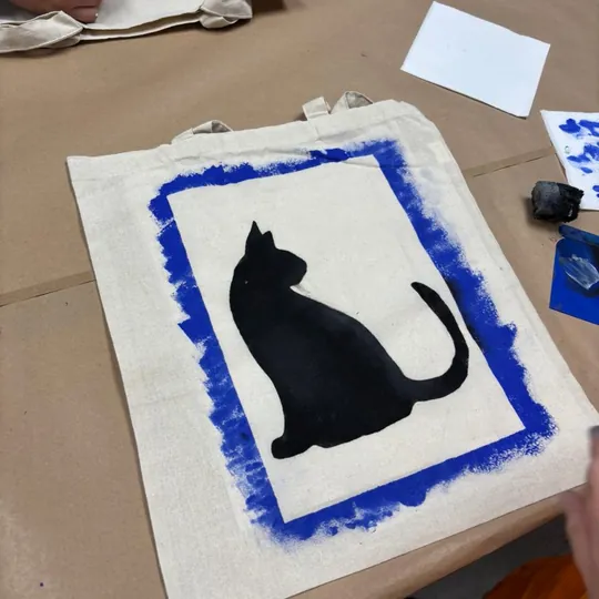 Bolsa pintada con un gato negro en el taller de tela