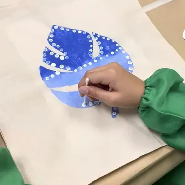 Niño pintando una bolsa de tela en el taller creativo