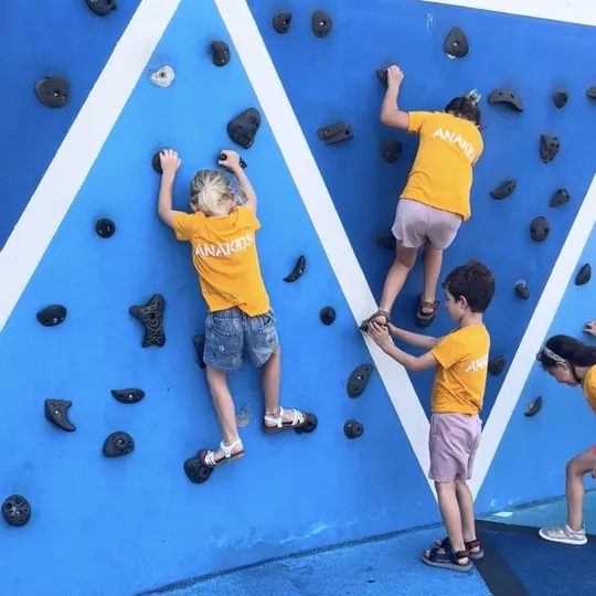 Niños escalando en el rocódromo durante las colonias